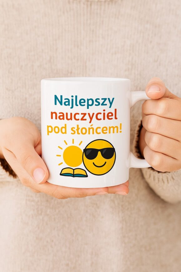 Osoba trzyma w dłoniach biały kubek z zabawną grafiką i napisem „Najlepszy nauczyciel pod słońcem” – prezent z przymrużeniem oka i nutą ciepła