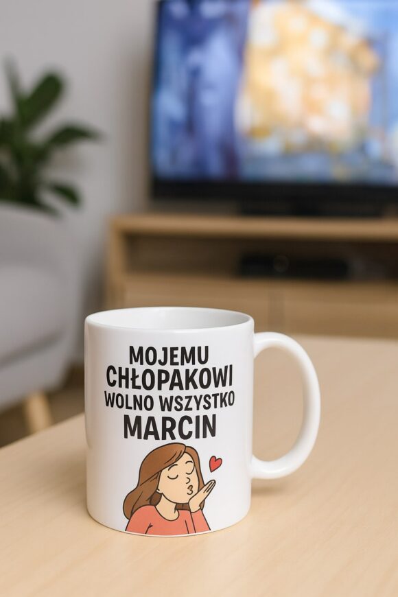 Kubek z nadrukiem Mojemu chłopakowi wolno wszystko Marcin na stole w salonie z telewizorem w tle